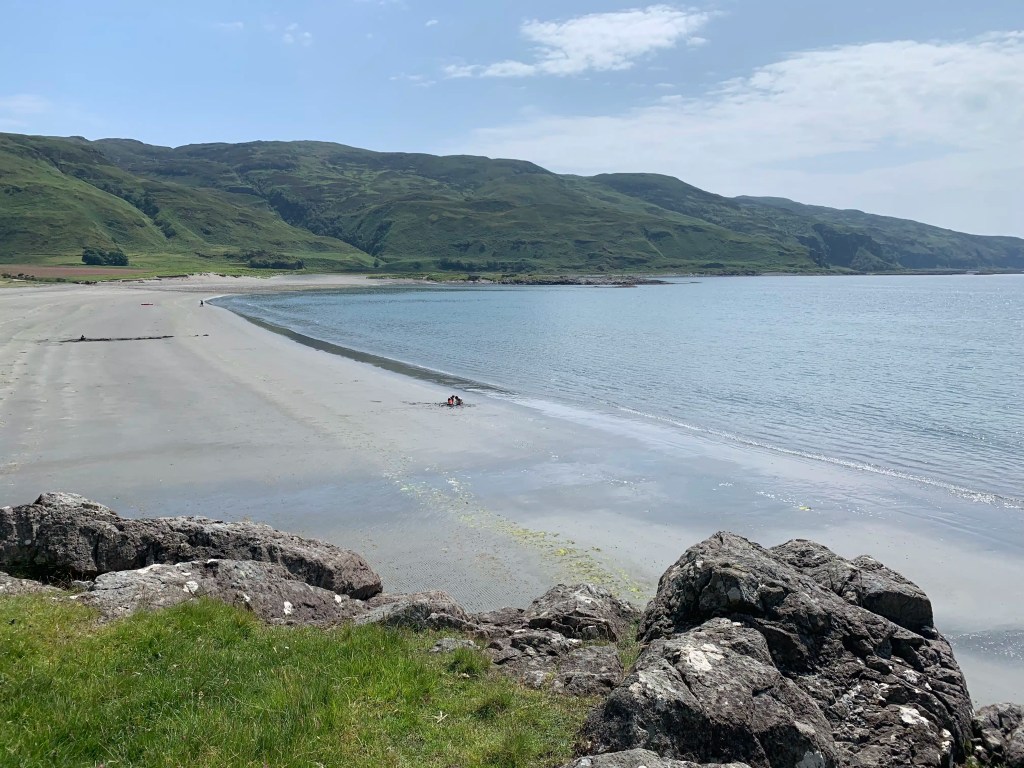 Scenic beach on Mull with green hills in the background, showcasing Wildlife on Mull.