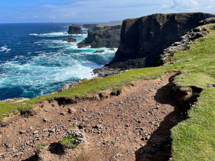 Shetland coastline view: Rugged cliffs meet the turquoise sea near Mainland & Mousa.