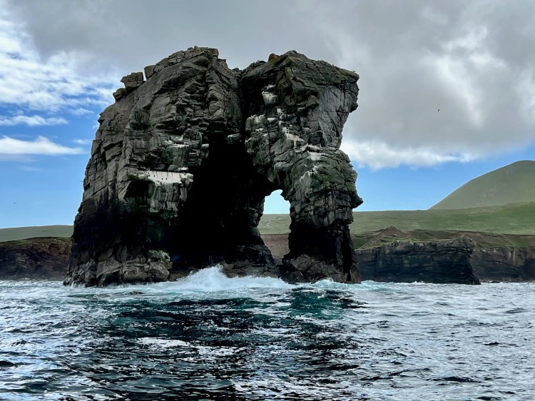 Foula sea arch, part of the Shetland Islands wildlife, with waves crashing at its base.