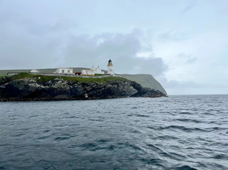 Noss Lighthouse on a rocky cliff overlooking the sea in Shetland.