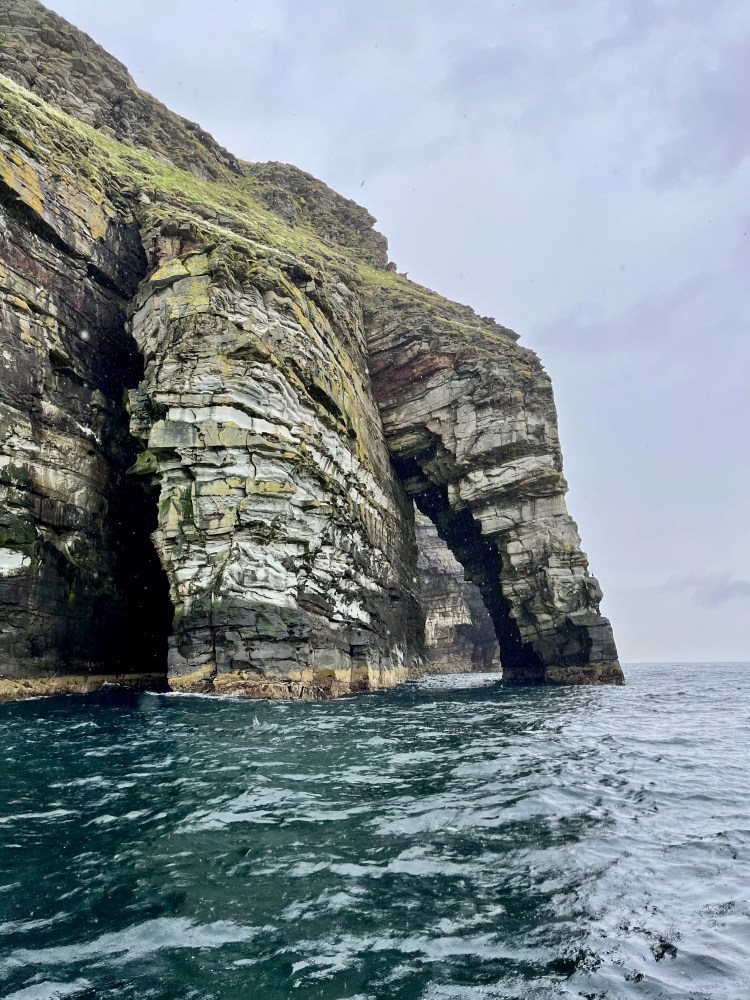 Noss sea cliffs with natural archway, viewed from the water. Shetland Wildlife.