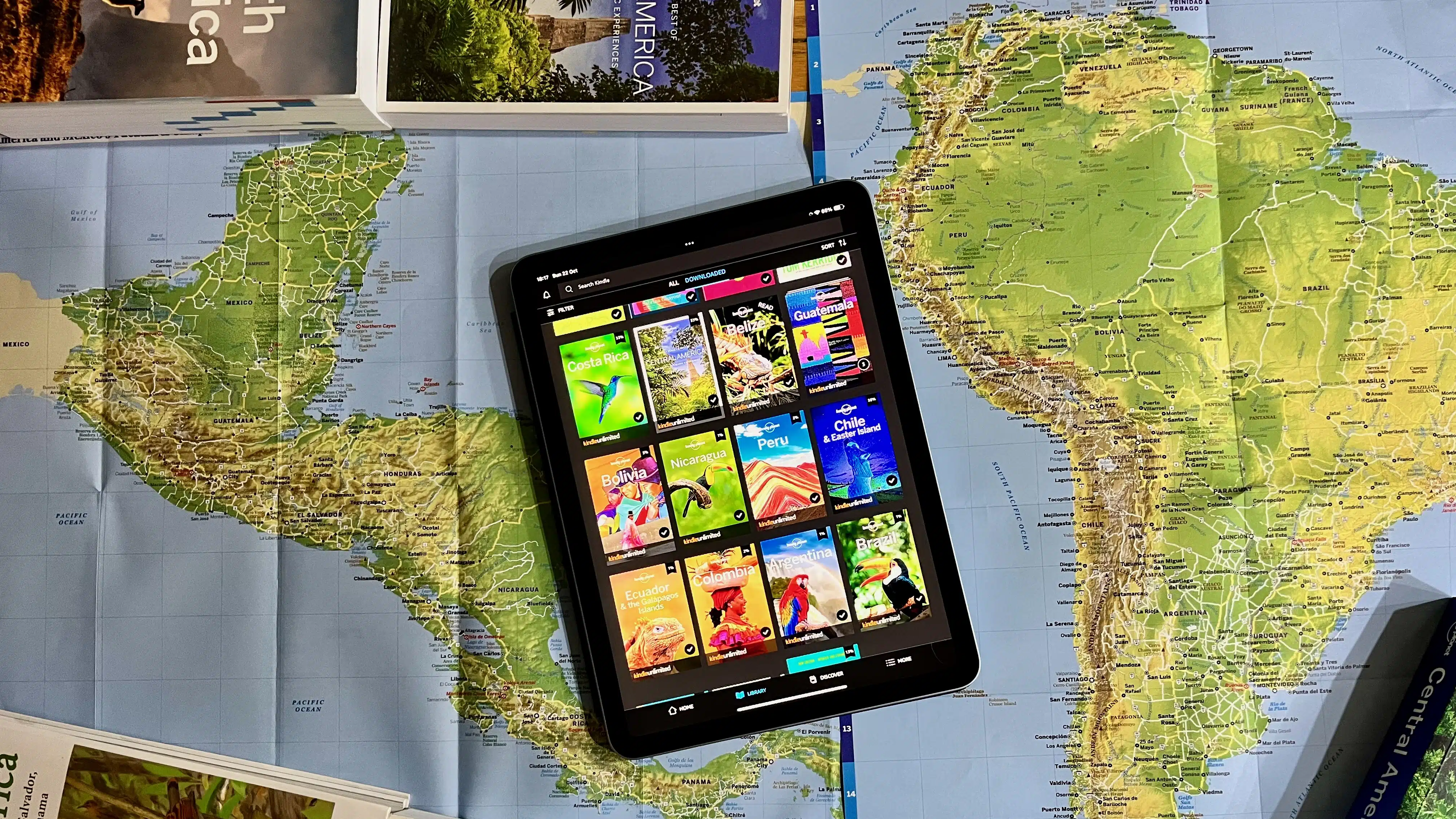 Tablet showing travel guides over a map of Central and South America.