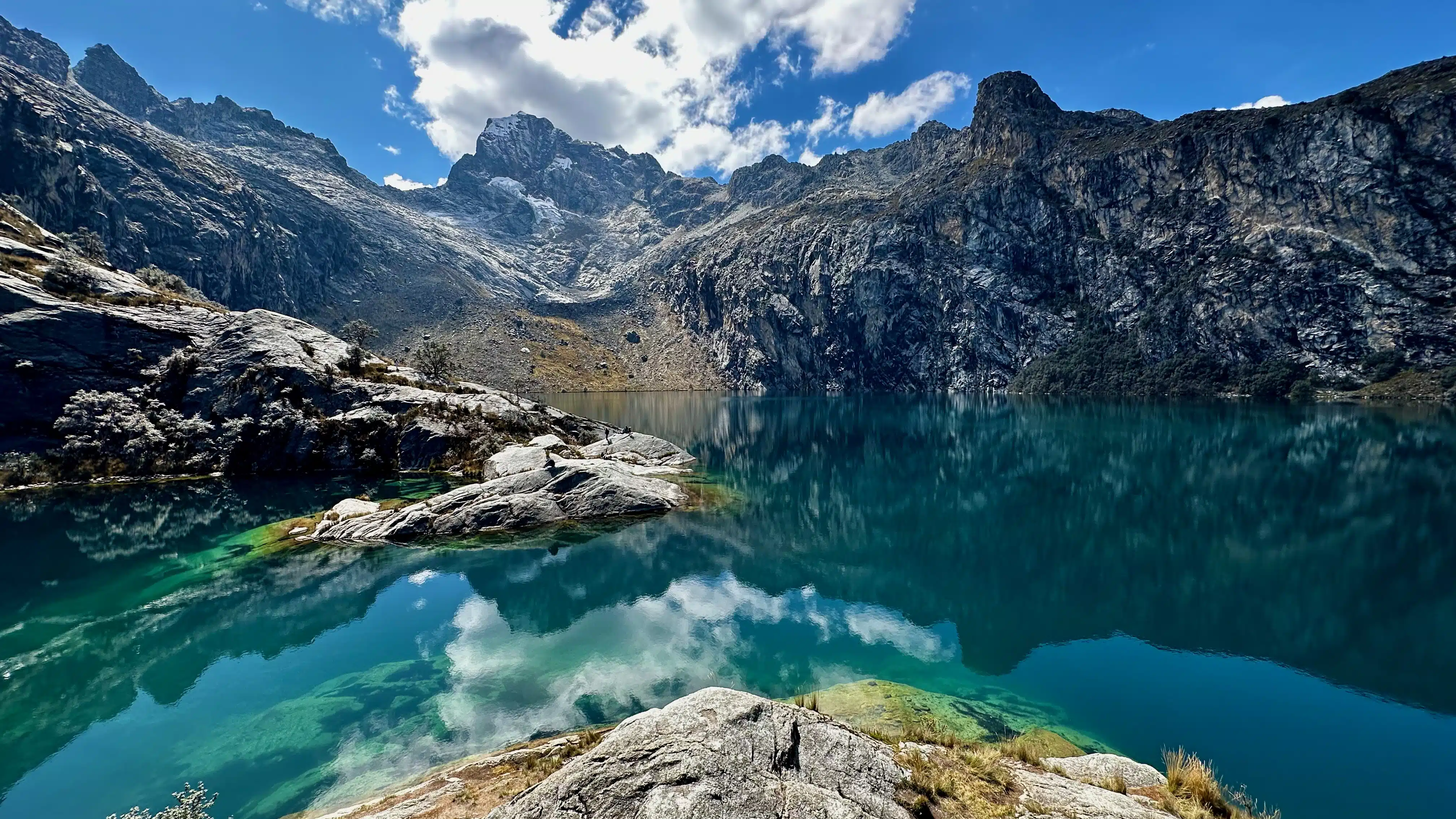 Turquoise mountain lake reflecting peaks and sky near Huaraz, Peru.